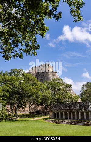 Blick auf die Pyramide des Magiers, eingerahmt von Bäumen, und das Nonnenkloster-Quadrangle in Uxmal, Yucatán, Mexiko. Stockfoto