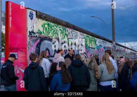 Tourgruppe mit einem Reiseleiter in der Berliner Wall East Side Gallery in Berlin, Deutschland. Stadttourismus, Gruppe von Touristen, Tourgruppe, geführte Tour. Stockfoto