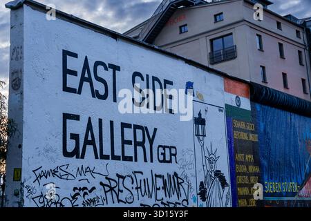 Redaktionelles Bild mit dem ersten Teil der East Side Gallery, einem erhaltenen Teil der Berliner Mauer, fotografiert in der Abenddämmerung in Berlin. Stockfoto
