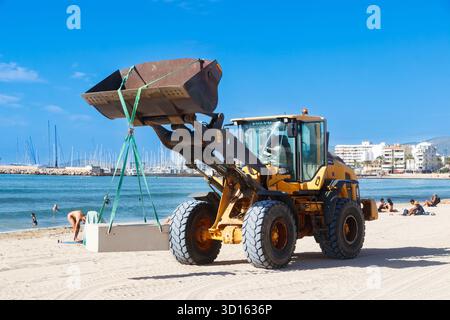 Baulader arbeitet am Sandstrand in c'an pastilla mallorca und senkt die Schutzmauern aus Betonblöcken Stockfoto
