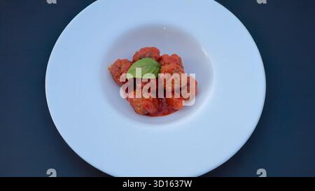 Hausgemachte Fleischbällchen in Tomatensauce mit Basilikumblatt Stockfoto
