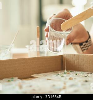 Weibliches Gießen von Harz in Form für handgefertigte Handwerksprojekte in Werkstätten. Stockfoto