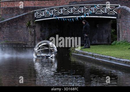 Dudley, West Midlands, Großbritannien. Oktober 2025. Eine faszinierende Flotte von drei beleuchteten, schwimmenden Skulpturen, Water Bots, an der Dudley No.2-Kanal-Kreuzung am Windmill End in der Nähe von Dudley im Herzen des industriellen Black Country, West Midlands. Der Künstler Michael Candy hat Water Bots als bahnbrechende Fusion von Kunst und Technik geschaffen. Es ist vom industriellen Erbe der Region West Midland inspiriert und wurde von Birmingham Open Media in Auftrag gegeben. Quelle: Peter Lopeman/Alamy Live News Stockfoto