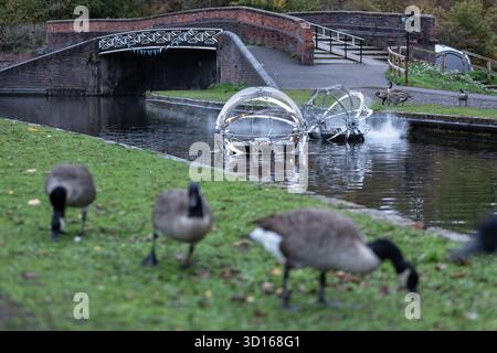 Dudley, West Midlands, Großbritannien. Oktober 2025. Eine faszinierende Flotte von drei beleuchteten, schwimmenden Skulpturen, Water Bots, an der Dudley No.2-Kanal-Kreuzung am Windmill End in der Nähe von Dudley im Herzen des industriellen Black Country, West Midlands. Der Künstler Michael Candy hat Water Bots als bahnbrechende Fusion von Kunst und Technik geschaffen. Es ist vom industriellen Erbe der Region West Midland inspiriert und wurde von Birmingham Open Media in Auftrag gegeben. Quelle: Peter Lopeman/Alamy Live News Stockfoto