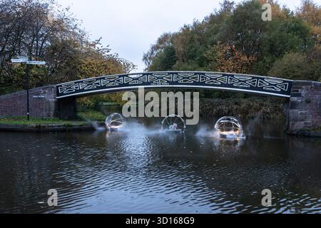 Dudley, West Midlands, Großbritannien. Oktober 2025. Eine faszinierende Flotte von drei beleuchteten, schwimmenden Skulpturen, Water Bots, an der Dudley No.2-Kanal-Kreuzung am Windmill End in der Nähe von Dudley im Herzen des industriellen Black Country, West Midlands. Der Künstler Michael Candy hat Water Bots als bahnbrechende Fusion von Kunst und Technik geschaffen. Es ist vom industriellen Erbe der Region West Midland inspiriert und wurde von Birmingham Open Media in Auftrag gegeben. Quelle: Peter Lopeman/Alamy Live News Stockfoto