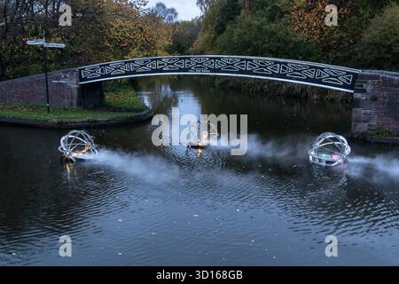 Dudley, West Midlands, Großbritannien. Oktober 2025. Eine faszinierende Flotte von drei beleuchteten, schwimmenden Skulpturen, Water Bots, an der Dudley No.2-Kanal-Kreuzung am Windmill End in der Nähe von Dudley im Herzen des industriellen Black Country, West Midlands. Der Künstler Michael Candy hat Water Bots als bahnbrechende Fusion von Kunst und Technik geschaffen. Es ist vom industriellen Erbe der Region West Midland inspiriert und wurde von Birmingham Open Media in Auftrag gegeben. Quelle: Peter Lopeman/Alamy Live News Stockfoto