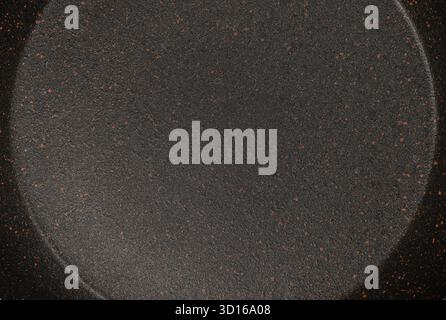 Nahaufnahme der Oberfläche einer dunklen, strukturierten Antihaftpfanne mit gesprenkelter Keramikgranitbeschichtung, ideal für Küchenutensilien, Kochkonzepte und Backgüsse Stockfoto