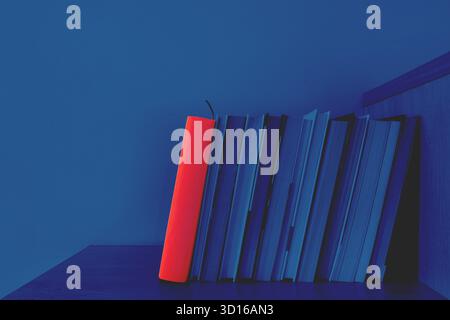 Freizeitkonzept. Ein Stapel Bücher steht auf einem Regal und wird von Nachtlicht beleuchtet. Ein Buch mit rotem Umschlag springt heraus. Retro-Vintage-STYLE Stockfoto
