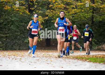 Gruppe von Frauen mittleren Alters, die fröhlich durch den Park joggen, umgeben von Herbstfarben, fördern Fitness Wellness und positiven Lebensstil im Freien. Stockfoto