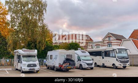 Winterswijk, Niederlande; 16. Oktober 2025: Moderne Mobilheime auf einem kleinen, versteckten Parkplatz, umgeben von Bäumen und alten Häusern unter einer violetten Ebene Stockfoto