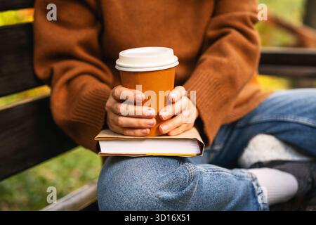 Frau hält Papierkaffeetasse und Bucht draußen im Stadtpark Stockfoto