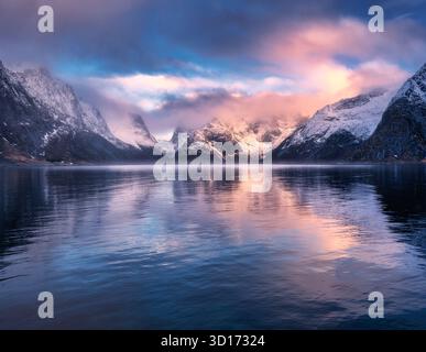 Farbenfroher Sonnenaufgang und schneebedeckte Berge spiegeln sich im Wasser Stockfoto