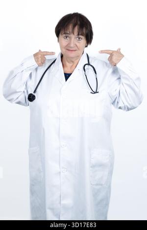 Leitende Ärztin mit weißem Labormantel und Stethoskop, zeigt mit beiden Zeigefingern auf sich selbst, was ihre Rolle und ihr Engagement in der Heilung andeutet Stockfoto