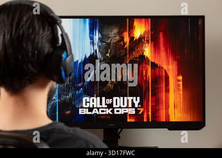 Nahaufnahme mit einem Mann rückwärts, der mit Ohrhörern einen pc-Monitor mit dem Videospiel Call of Duty Black OPS 7 ansieht Stockfoto