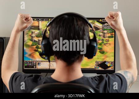 Ganz nah an den Rückwärter eines Mannes, der auf einem pc einen Sieg in das Strategievideo Age of Empires 2 feiert Stockfoto