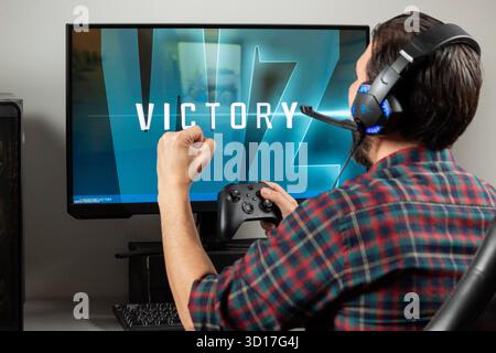 Nahaufnahme eines männlichen Spielers auf der rechten Seite des Bildes, der einen Sieg des Videospiels Call of Duty Warzone Shooter in einem Computer feiert Stockfoto