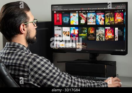 Nah an einem Mann hinten links im Bild, der ein Video auf einer Streaming-Plattform in einem Computer sucht Stockfoto
