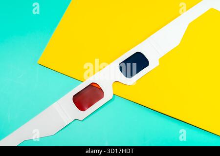 Eine 3D-Brille steht vor einem leuchtenden Gelb- und Aqua-Hintergrund und symbolisiert Kino und Unterhaltung. Stockfoto