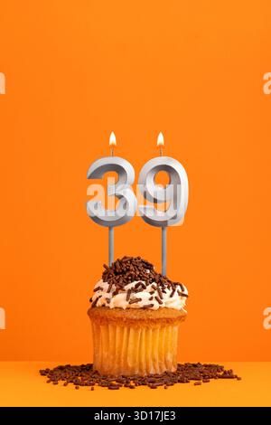 Geburtstagskerze Nummer 39 - Einladungskarte mit orangem Hintergrund. Cupcake Stockfoto