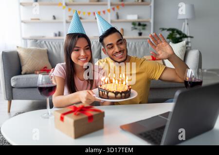 Das Paar feiert den Geburtstag virtuell mit Kuchen und Dekorationen, während es sich auf ein Videogespräch vorbereitet Stockfoto