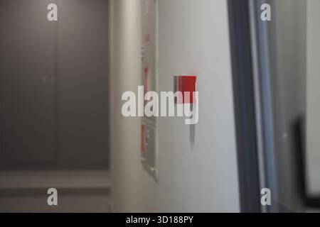 Rote Alarmtaste an der Wand in einem ruhigen Flur Stockfoto