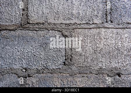 Eine detaillierte Nahaufnahme einer Wand aus Betonblöcken (Schlackenblöcken). Der raue Mörtel und die grobe, körnige Oberfläche schaffen ein perfektes industrielles grun Stockfoto