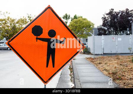 Orangefarbenes Verkehrswarnschild, das Kraftfahrzeuge auf vor Straßenarbeiten warnt und bereit ist, anzuhalten. Stockfoto