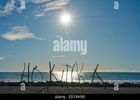 Strichschild Hokitika am Strand Hokitika, der von einer untergehenden Sonne beleuchtet wird, Westküste, Südinsel, Aotearoa / Neuseeland. Stockfoto