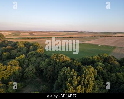 Bergnicourt, Rethel, Ardennes, Grand-Est, Frankreich, August, 28. August 2025, ein Blick aus der Vogelperspektive zeigt lebendiges Ackerland und üppiges Grün unter einem atemberaubenden Sonnenuntergang, was eine ruhige Landschaft schafft Stockfoto