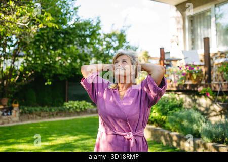 Schöne ältere Frau, die Yoga im Garten macht, Morgenroutine. Stockfoto