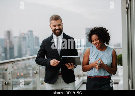 Zwei Geschäftsleute unterhalten sich auf der Dachterrasse des modernen Büros Stockfoto