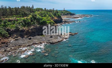 Klippen und blaue Küstengewässer mit Leuchtturm, Quang Ngai, Vietnam – aus der Vogelperspektive Stockfoto
