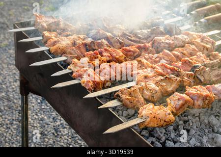 Ein Grill mit Fleisch drauf und viel Rauch drauf. Das Fleisch wird auf Spießen gekocht Stockfoto