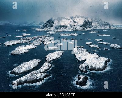 Blick aus der Vogelperspektive über die wunderschönen Henningsvaer Lofoten Inseln, Norwegen, Winterlandschaft des Schnees über kleinen Inseln im Meerwasser Stockfoto