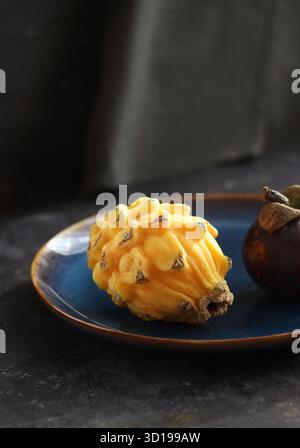 Gelbe pitaya und Mangostan liegen auf einem Teller auf dem Tisch Stockfoto
