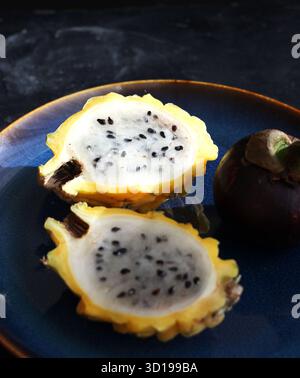 Gelbe pitaya und Mangostan liegen auf einem Teller auf dem Tisch Stockfoto