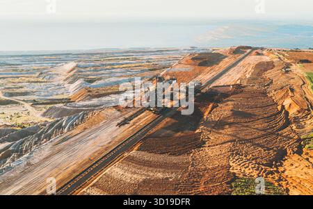 Aus der Vogelperspektive gravieren sich massive Bagger tief in die geschichtete Erde und bilden einen starken Kontrast zum fernen Horizont, Tagebau Hambach, Nordrhein-Westfalen. Stockfoto