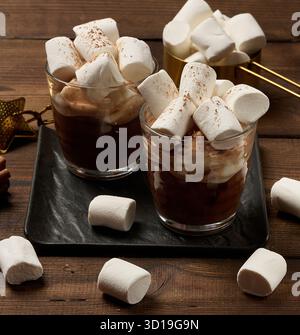 Zwei Gläser heiße Schokolade mit flauschigen Marshmallows auf einem Schieferbrett. Eine Nahaufnahme des Wintergetränks. Stockfoto