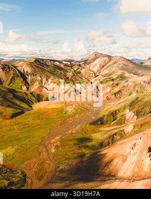 Aus der Vogelperspektive auf die zerklüfteten, bunten Rhyolithberge und gewundenen Flüsse schaffen einen Wandteppich aus Texturen und Tönen, Landmannalaugar, Rangárþing ytra, Island. Stockfoto
