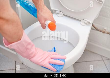 Ein Mann wäscht eine Toilette. Er reinigt die Toilette, um Sauberkeit und Hygiene zu gewährleisten. Stockfoto