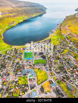 Aus der Vogelperspektive auf Häuser eingebettet zwischen üppig grünen Hügeln und dem ruhigen blauen Wasser einer Bucht, Klaksvík, Nördlichen Inseln und Färöer Inseln. Stockfoto