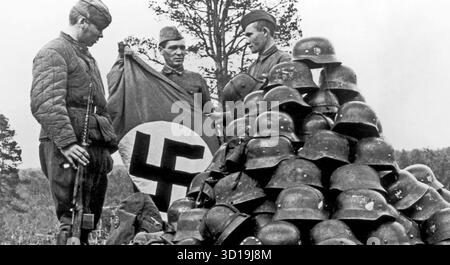 Russische Soldaten mit gefangengenommenen Nazi-Helmen und einer Flagge um 1943. Foto: SIB Stockfoto