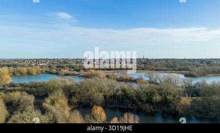 Aus der Vogelperspektive über Irthlingborough Lakes and Meadows in den Nene Wetlands, Northamptonshire, mit Higham Ferrers in der Ferne. Stockfoto
