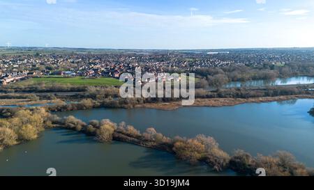 Blick aus der Vogelperspektive über das Naturschutzgebiet Irthlingborough Lakes and Meadows in den Nene Wetlands, Northamptonshire, mit der Stadt Irthingborough im Hintergrund. Stockfoto