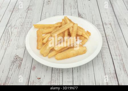 Außen knusprig, innen flauschig gebratener Yuca, serviert mit Koriander, Knoblauch und Zitronenmojo-Sauce zum Dippen Stockfoto