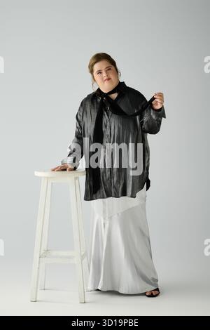 Eine junge Frau mit Down-Syndrom zeigt ihr Selbstvertrauen und ihre Mode in einem kreativen Studio. Stockfoto