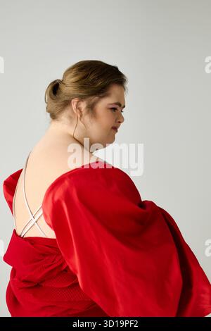 Eine junge Frau mit Down-Syndrom zeigt ihre Individualität in einem leuchtend roten Outfit. Stockfoto