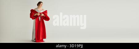 Eine junge Frau mit Down-Syndrom zeigt ihre Eleganz in einem kühnen roten Kleid und strahlt Freude aus. Stockfoto