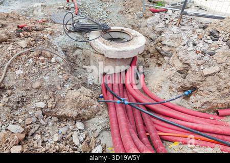 Verlegung der Kommunikation in den Boden mit roten Wellschläuchen. Stockfoto