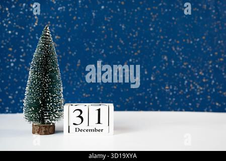Einfache elegante Komposition mit hölzernem Weihnachtsbaum und Kalender mit Dezember 31. Ideal für Silvester Countdown und festliche Marketinggrafiken. Stockfoto